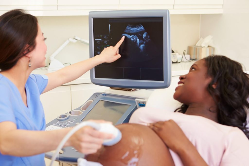 Nurse examines an ultrasound of an infant in the womb of its mother.