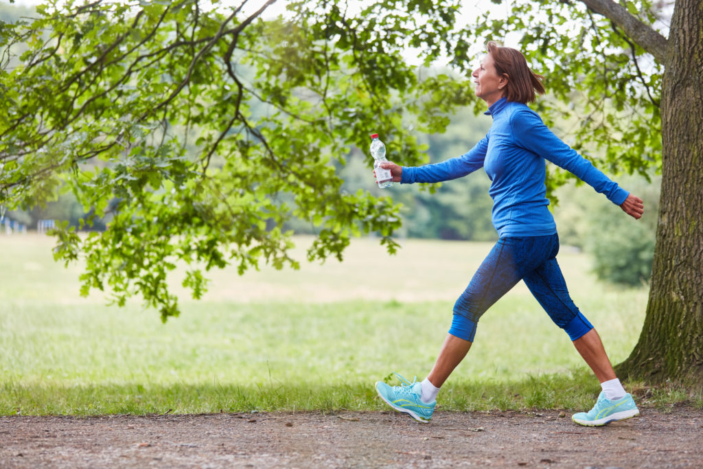 a middle aged woman going for a walk in a lush park